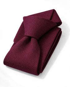 Folded burgundy tie on a white background