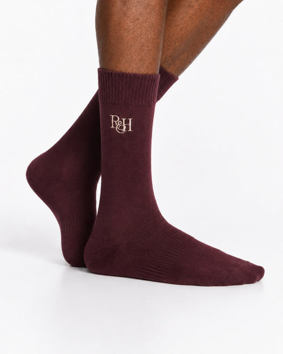 Maroon socks with a logo on the leg against a white background