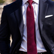 Man wearing a dark suit with a white shirt and red tie.