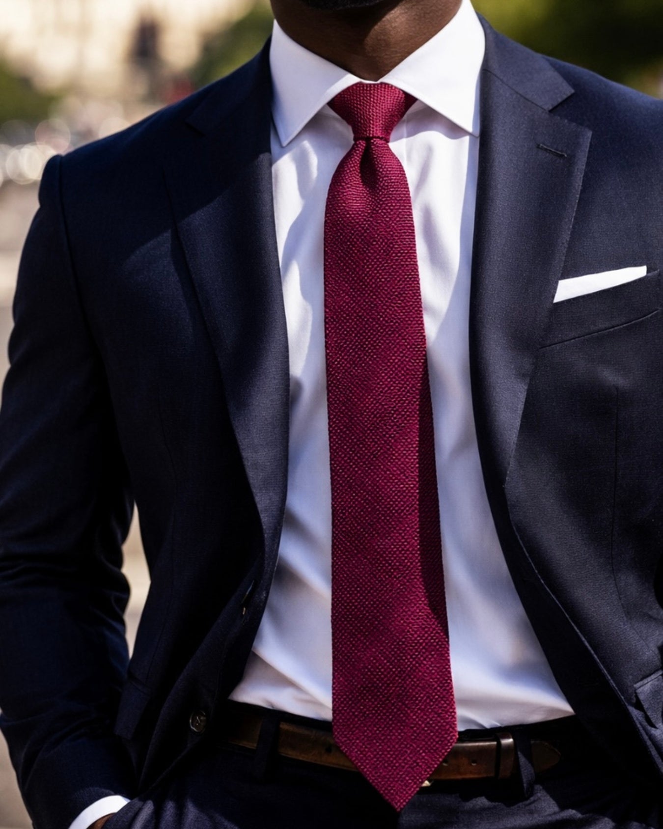 Man wearing a dark suit with a white shirt and red tie.