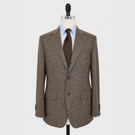 A brown and beige houndstooth patterned blazer displayed on a mannequin torso, styled with a brown tie and a blue-and-white striped shirt against a light gray background.