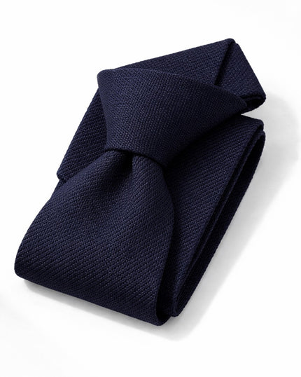 Folded navy blue tie on a white background