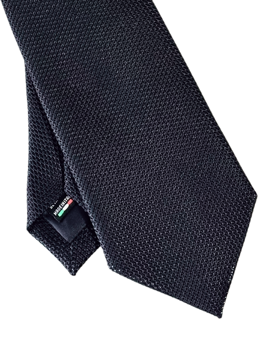A close-up of a dark navy blue textured necktie with a small Italian flag tag on the collar end, set against a plain white background.