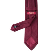 Maroon tie with a brand label on a white background
