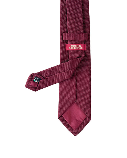 Maroon tie with a brand label on a white background