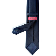 Navy textured tie with a pink label on a white background