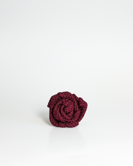A small burgundy textured fabric rose lapel accessory, centered on a clean white background.